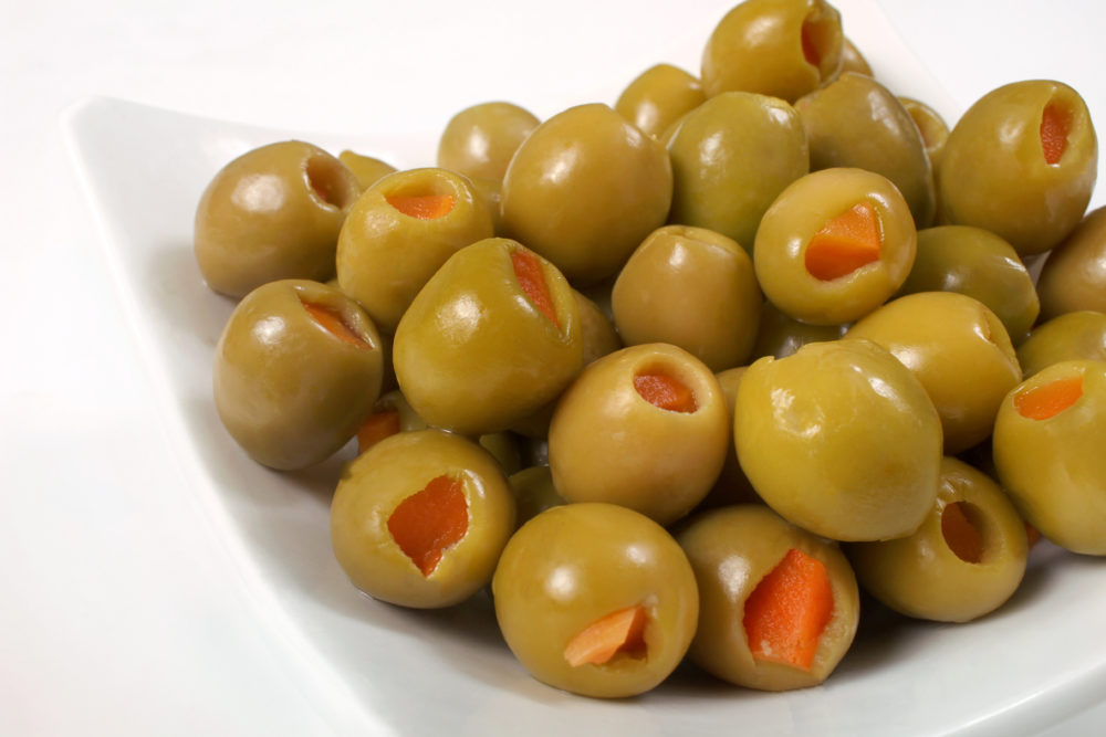 A close-up shot of a white dish filled with carrot-stuffed green olives