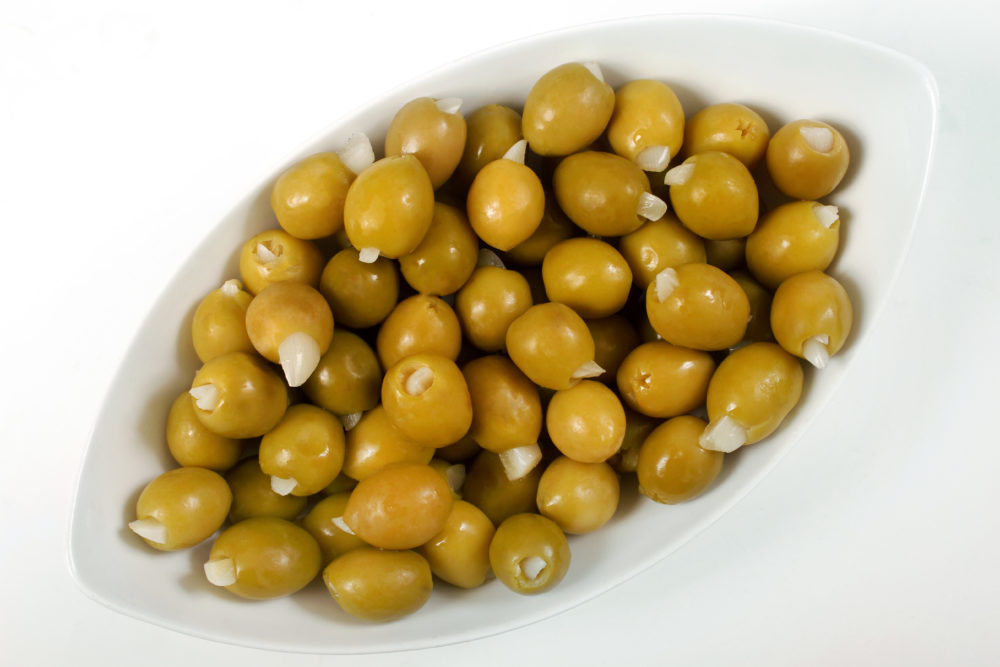 A white dish filled with garlic-stuffed green olives