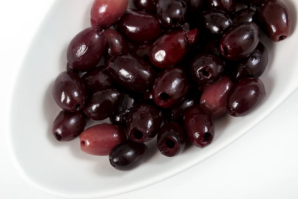 A white dish filled with pitted Kalamata-style olives