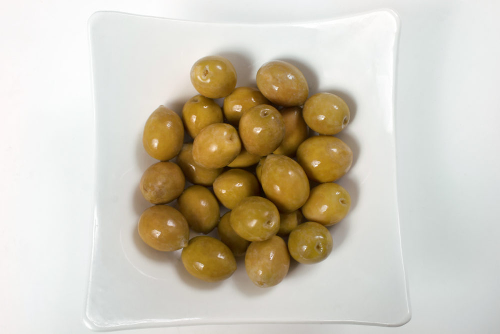 A white plate filled with a handful of unpitted, naturally-cured green olives