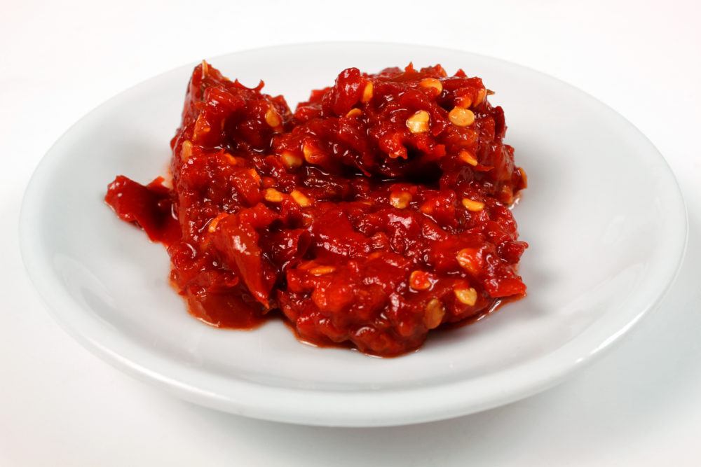 A small amount of shuttah, a red chili pepper sauce made with Aleppo Peppers, on a white plate